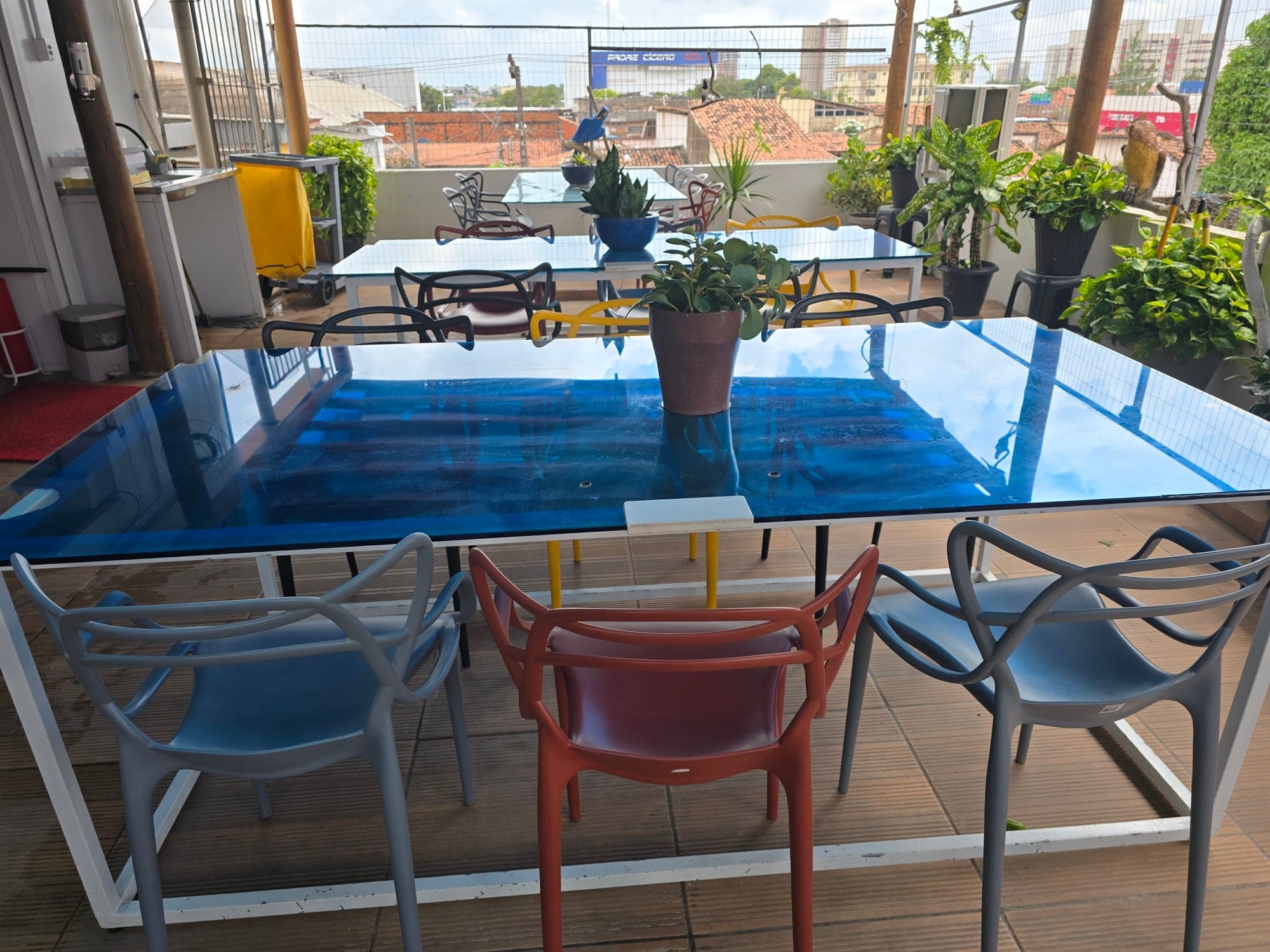 Mesas do rooftop do Coworking Parquelândia em Fortaleza — reunião informal ao ar livre